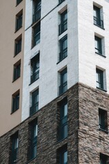 Modern apartment building with a mix of white and brown brick, showcasing balconies and large windows against a clear sky