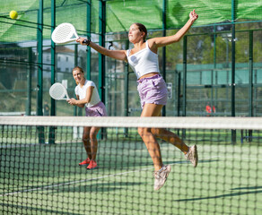 Active womans with enthusiasm playing padel on the tennis court