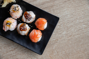 Temarizushi or Japanese rice balls served on the black plate in the restaurant Temari zushi with shrimp, crab, salmon, eel. Japanese Temarizushi. Selective focus.