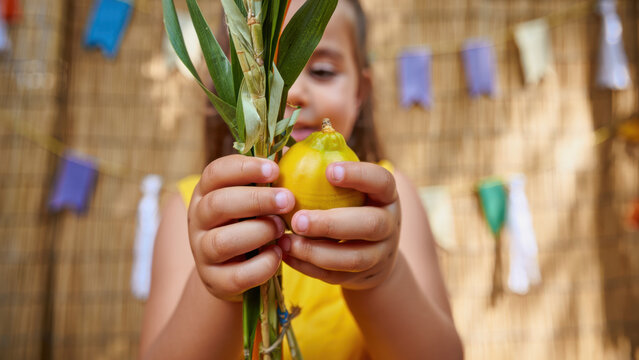Jewish Sukkot celebration, child holding lulav and etrog, joyful tradition, autumn festival, religious holiday, cultural heritage, festive background, family gathering, spiritual unity