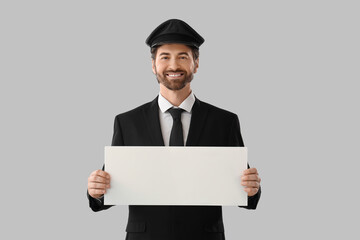 Handsome chauffeur with blank banner on grey background