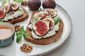 Sandwiches with figs, cream cheese, basil and honey on plate