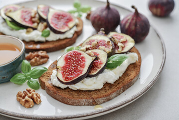 Sandwiches with figs, cream cheese, basil and honey on plate