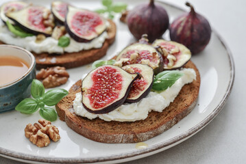 Sandwiches with figs, cream cheese, basil and honey on plate