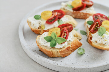 Bruschetta sandwiches with tomatoes, cream cheese, olive oil and basil on a plate