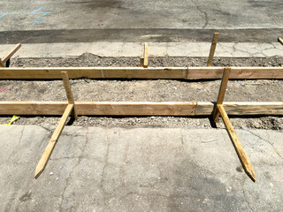 Wooden framing and supports for freshly excavated sidewalk construction site, prepared for pouring concrete along city street