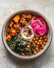 A vegan buddha bowl with roasted sweet potato, chickpeas, kale and tahini swirl on speckled stoneware.