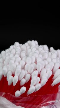 Vertical video cotton swabs rotating, cotton buds close up shot on black background. Personal hygiene and cosmetic items. Ear cleaning q tips