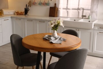 Dining table, chairs and floral decor in kitchen. Interior design