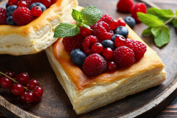 Yummy puff pastries with berries on table, closeup