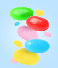 Sweet jelly beans falling against light blue background