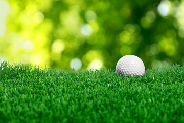 Golf ball on green grass against blurred background