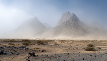 Vast arid desert landscape with towering dusty mountains under a hazy sky.