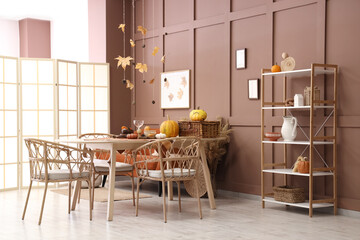 Interior of stylish dining room with table, sofa and autumn leaves