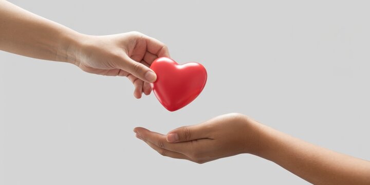 Hands exchanging a red heart, symbolizing love, care, and donation, isolated on white background, representing giving, support, and compassion