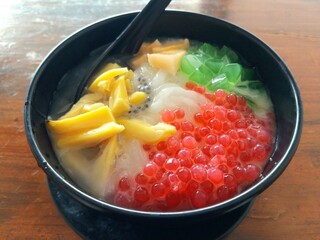 Es Teler, a popular Indonesian dessert served in a black bowl, featuring shaved ice with toppings such as jackfruit, grass jelly, tapioca pearls, and sweet condensed milk.