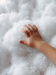 Child's hand touching soapy water in a bathtub