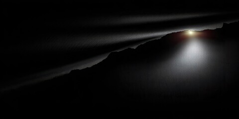 Silhouette of a mountain range bathed in a spotlight, emanating from a bright light source