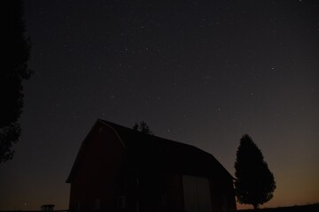 nighttime sky with stars and a barn in the foreground