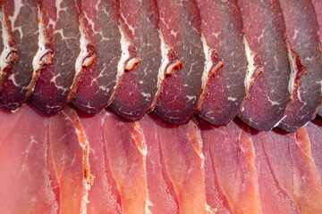 An artistic arrangement of cured meat slices in rows, showcasing their textures and color variations. ideal for culinary, cooking, and food-related themes.