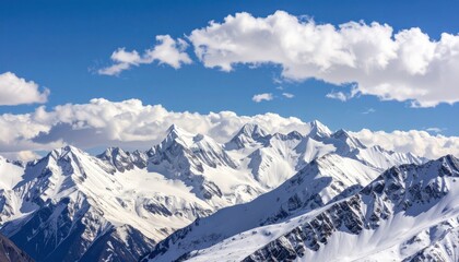 Obraz premium Majestic mountain range covered in fresh snow under a bright blue sky dotted with fluffy white clouds on a sunny day