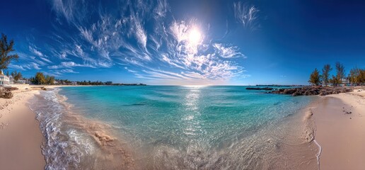 Panoramic view of a tropical beach with turquoise water, white sand, and wispy clouds under a bright sun on a clear day