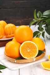 Fresh Sweet Oranges in Wooden Basket with Green Leaves on Marble Board