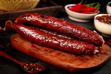 Homemade Smoked Sichuan Sausage on Wooden Board with Traditional Chinese Spices and Red Chili Peppers