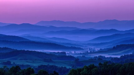 Fototapeta premium Layers of blue mountains covered in fog create a beautiful landscape at dawn with a pink sky