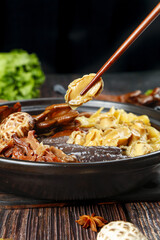 Traditional Asian Hot Pot with Chopsticks Picking Up Food from Steaming Broth Bowl