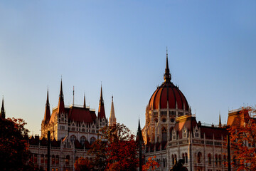 Hungarian Parliament Building stands majestically against clear sky during sunset, surrounded by...