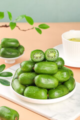Fresh Mini Kiwi Berries in Bowl with Green Tea on Wooden Table - Healthy Organic Fruit Snack