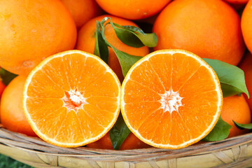 Fresh Ripe Oranges with Green Leaves in Wicker Basket Showing Juicy Cross-Sections