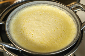 Heating pure cow’s milk using a water-bath double boiler: a stainless pot of milk sits over boiling water for gentle heating to prevent scalding and prepare dairy products