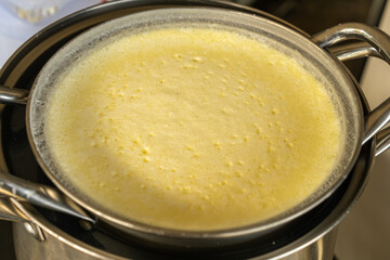 Heating pure cow’s milk using a water-bath double boiler: a stainless pot of milk sits over boiling water for gentle heating to prevent scalding and prepare dairy products