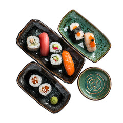 Assortment of traditional Japanese sushi and nigiri arranged on dark and green ceramic plates, top-down view.
