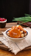 Traditional braised pork trotter with secret sauce and tofu in ceramic bowl on wooden table