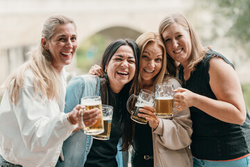A joyful group of friends drinks beer and celebrates together in a Bavarian beer garden during summer sharing fun laughter culture and tradition