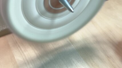 A close-up of a person's hand polishing a coin with a rotating wheel, showcasing craftsmanship and attention to detail