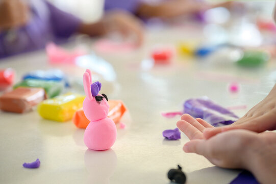 Children making colorful playdough animal figure in classroom, hands shaping creative clay art, preschool education and craft skills, fun learning activity with modeling clay.