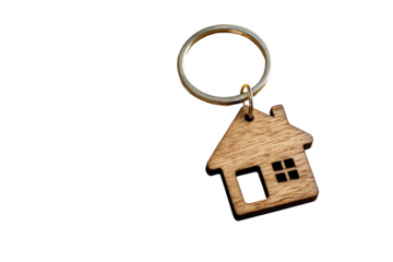 A wooden house-shaped keychain hangs from a metal ring against a black background.  The keychain is a simple, light brown wooden cutout of a house with a small window