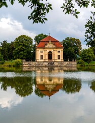 Elegant pavilion reflects on placid lake, framed by trees