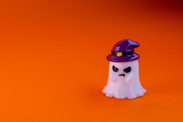 ghost wears a purple witch hat with evil look on an orange background under dramatic spotlight. Playful Halloween-themed decoration, perfect for seasonal advertising, greeting cards