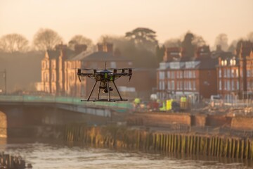 A drone flies over a river near a construction site and buildings at sunset, capturing aerial footage in an urban setting