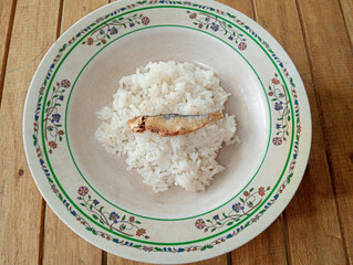 rice with salted fish on floral plate. White rice with fried salted fish on a floral plate, simple traditional Asian food.