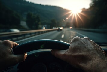 Hands grip a car steering wheel, driving on a road into the rising sun, with distant mountains, creating a sense of adventure and freedom