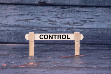 Control symbol. Wooden stick fastened by Clothespins, A lightly orange toned grunge wooden background. Business and Control concept with copy space
