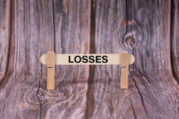 Losses symbol. A wooden stick clasped by clothespins set over a beautiful Brown Grunge Wooden Texture Background. Business and Losses concept with copy space