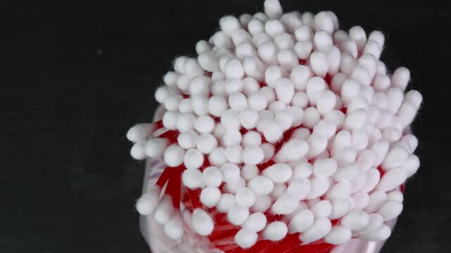 Cotton swabs rotating, cotton buds on black background top view. Personal hygiene and cosmetic items. Ear cleaning q-tips