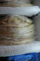 Stacked pizza wrapped in plastic for storage in a fridge 